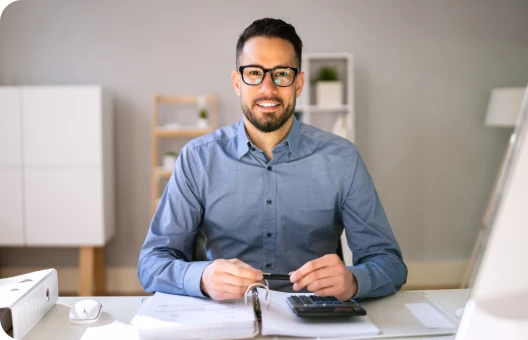 Un reclutador ejecutivo escribiendo en una computadora portátil con una calculadora y monedas.